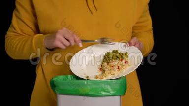 女人用盘子刮一个鸡腿，米饭，青豆放进垃圾桶